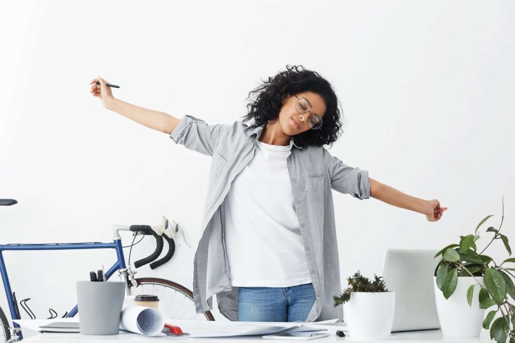 The Love Central - Beautiful dark-skinned woman having tired expression after hard work in office feeling relax stretching her hands isolated over white background. Busy student feeling relax after working at diploma The Love Central -