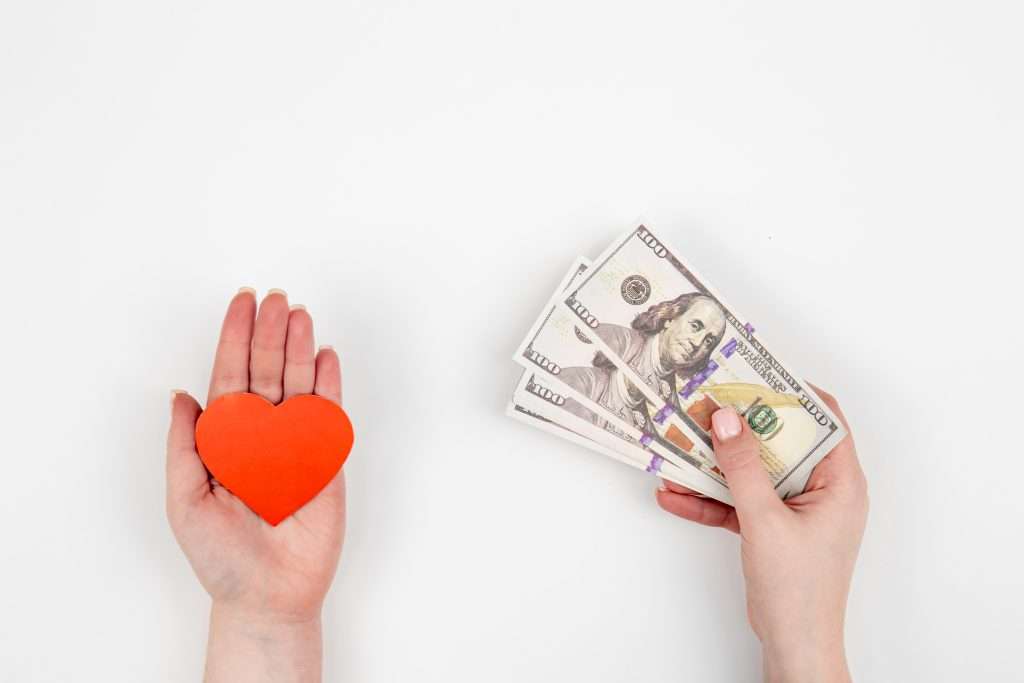 The Love Central - Hand with paper heart and a gift box on a white background isolated, flat lay. The Love Central -