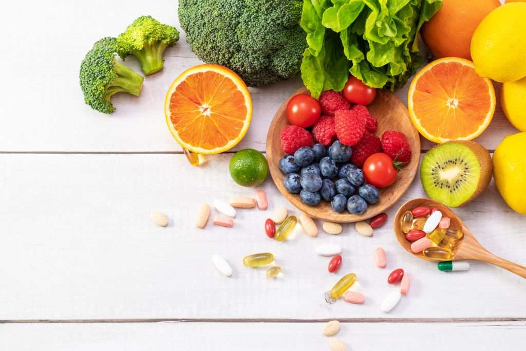 The Love Central - Top view of fresh fruits and vegetables with different medicine on a wooden spoon The Love Central -