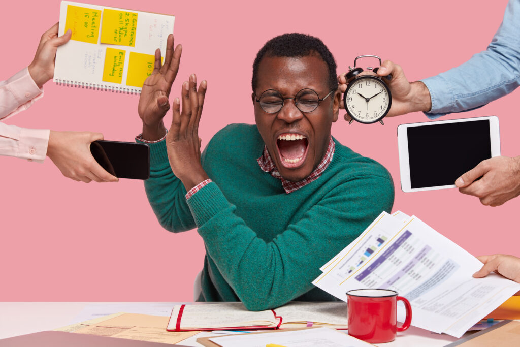 The Love Central - Indoor shot of desperate young Afro American man screams desperately, makes stop gesture, dressed in green sweater, busy working, isolated over pink background. People, work, depression concept The Love Central -