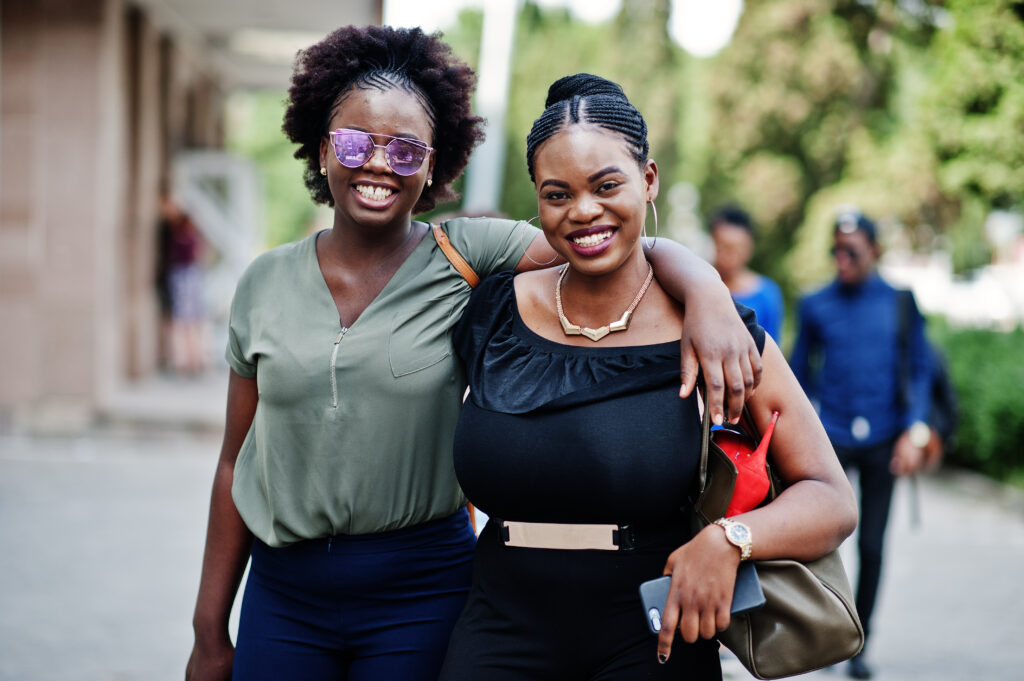 The Love Central - Two african american girls walking and posed at street of city. The Love Central -