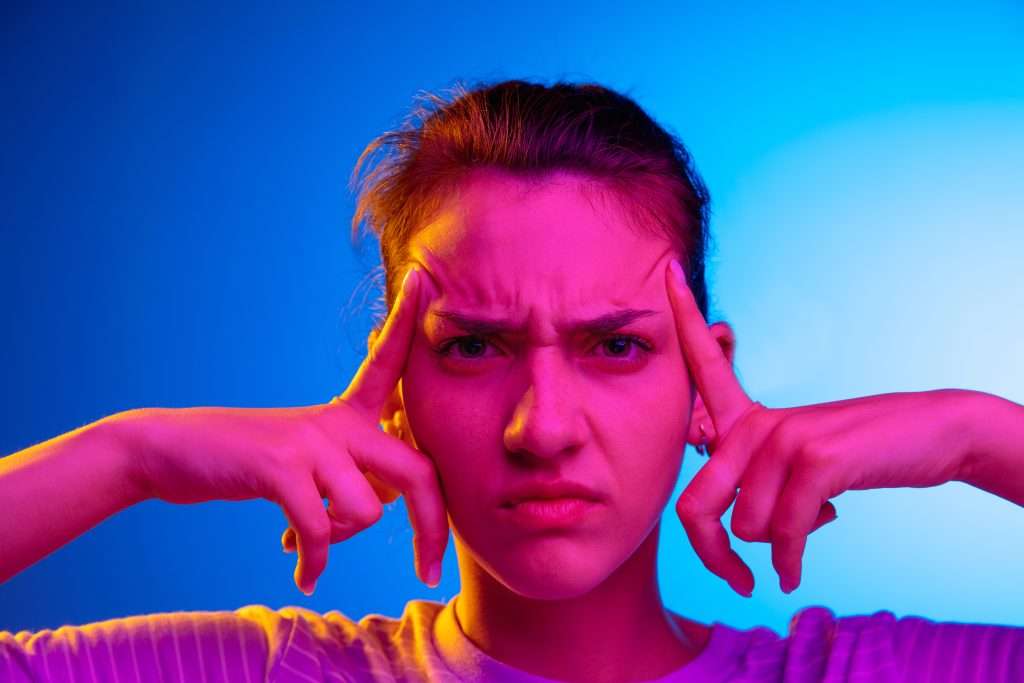 The Love Central - Woman having headache. Isolated on pink background. Businesswoman standing with pain isolated on trendy studio background. Female portrait. The Love Central -