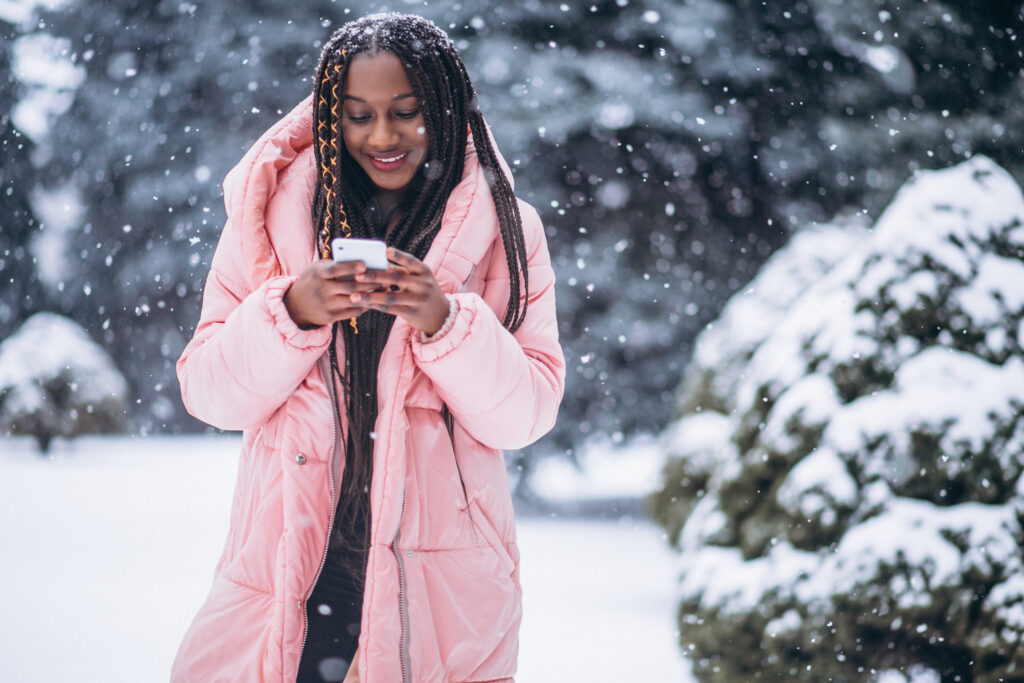 The Love Central - African american woman using phone ouside the street on a winter day The Love Central -