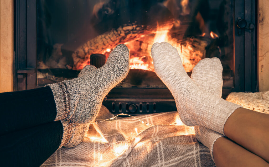 The Love Central - Women's feet in warm socks warm themselves by the home fireplace. The Love Central -