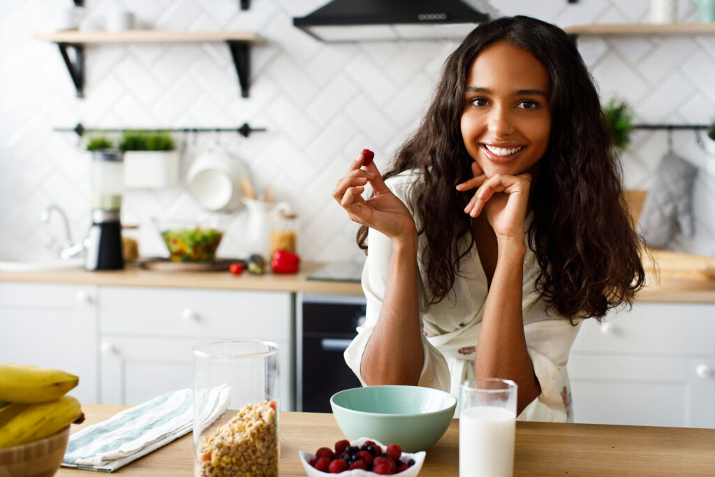 The Love Central - Smiled attractive mulatto girl is holding raspberry near the tab The Love Central -
