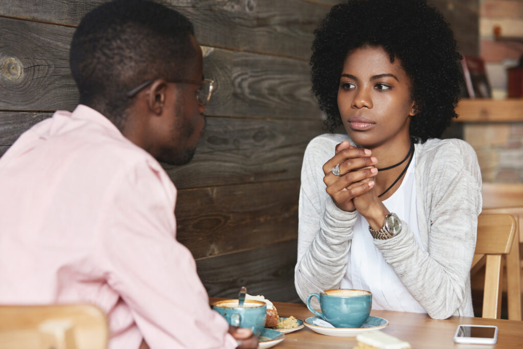The Love Central - Close up portrait of African American friends at cafe having serious conversation, fashionable hipster woman with Afro hairstyle looking at her boyfriend with puzzled and thoughtful face expression How to Talk Your Way to Romance