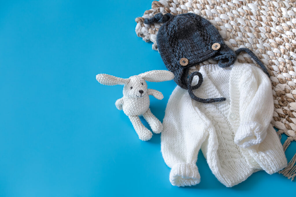 The Love Central - Knitted baby clothes and accessories on a blue background . The Love Central -