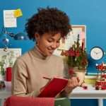 The Love Central - Pleased young African American woman writes down notes in diary.