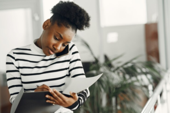 A black lady answering a phone call and documenting in a diary.