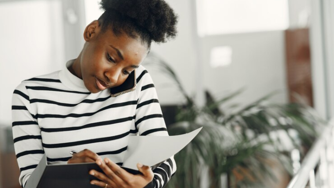 A black lady answering a phone call and documenting in a diary.
