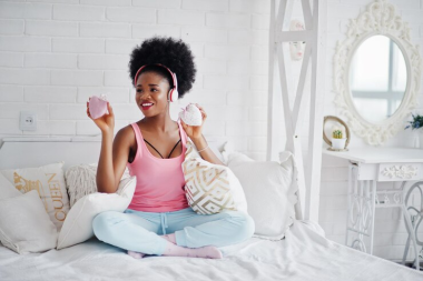 A happy lady enjoying music on her bed.