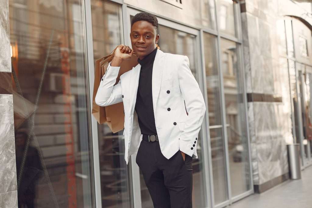 The Love Central - Black man in a white jacket with shopping bags How to Dress to Impress and Attract the Right Partner