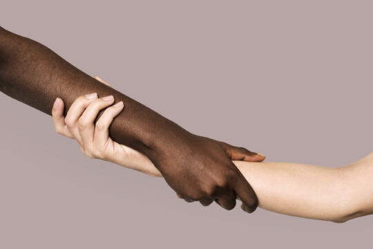 Diverse hands holding and supporting one another.