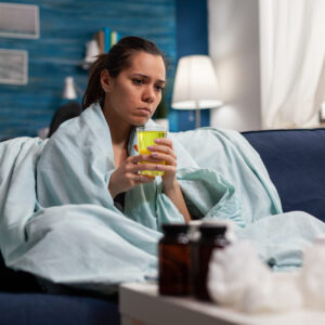 The Love Central - Caucasian woman sitting at home taking medicine for virus infection The Love Central -