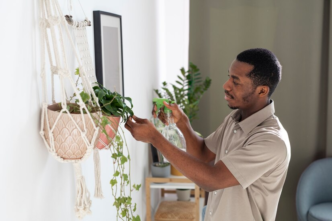 A man watering the plants in his living space