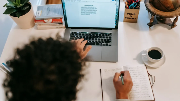 A lady with her laptop and writing materials.