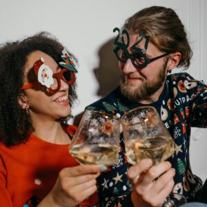 The Love Central - A happy couple smiling while looking at themselves while both holding glasses half filled with wine