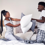 The Love Central - Couple playing with pillows on the bed