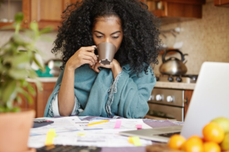 A lady calculating her finances while drinking coffee