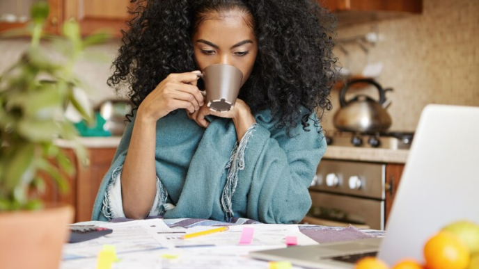 A lady calculating her finances while drinking coffee