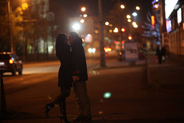 The Love Central - Lovers kissing and cuddling on a city street with passers The Love Central -